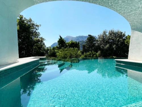 een zwembad met blauw water en bomen op de achtergrond bij Terrazza Tragara in Capri