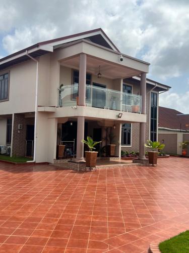 a large house with a balcony and a brick driveway at Boulevard Court in Ejisu
