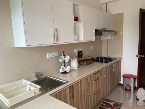 a kitchen with white cabinets and a sink at Beach Bliss in Trincomalee