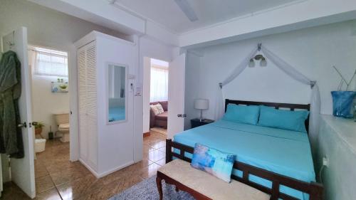 a bedroom with a blue bed and a chair at The Suite Spot Apartment - Private Paradise Stay in Soufrière