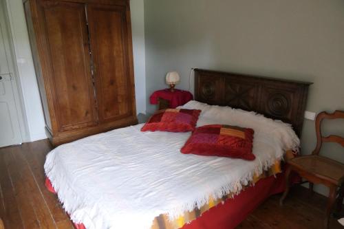um quarto com uma cama com duas almofadas vermelhas em la chambre du moulin de la bleure em Moncoutant