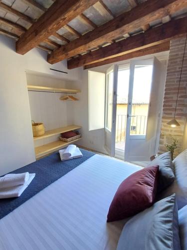 a large bed in a room with a large window at FeelhomeVIC. Ático con terraza en centro histórico in Vic