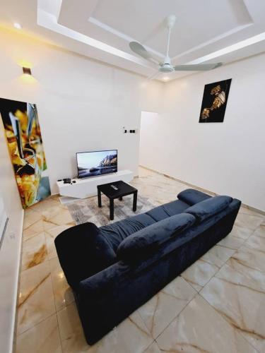 ein großes Sofa im Wohnzimmer mit einem TV in der Unterkunft Domicile Houéyiho in Cadjèhoun