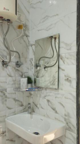uma casa de banho branca com um lavatório e um espelho em आंगण होम स्टे em Malvan