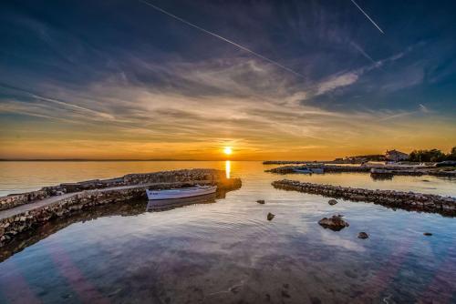 a sunset over a body of water with a boat at Privlaka Mobilhouses in Privlaka