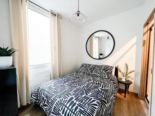 a bedroom with a bed with a black and white comforter and a mirror at Confort & modernité au centre de Tarbes in Tarbes