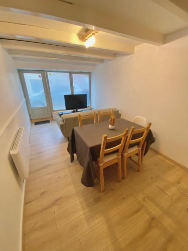 une salle à manger avec une table, des chaises et une télévision dans l'établissement Vesoul appartement atypique centre ville., à Vesoul