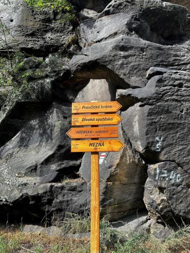 a wooden pole with several signs on a mountain at Stara Plynarna in Hřensko