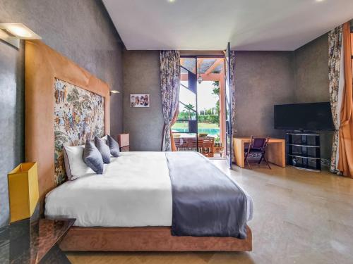 a bedroom with a large bed and a television at Villa de luxe service compris in Marrakesh