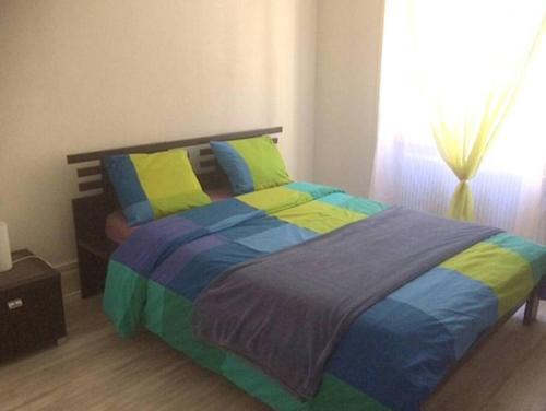 een slaapkamer met een bed met kleurrijke lakens en een raam bij Agréable F3 - RDC (2 chambres) in Mulhouse