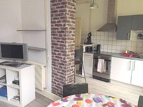 une cuisine avec un mur en briques et une table avec un ordinateur dans l'établissement Agréable F3 - RDC (2 chambres), à Mulhouse