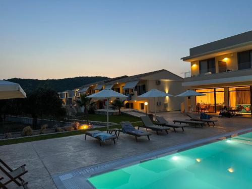 a pool with chairs and umbrellas next to a building at Apartments Villa Rania in Perdika