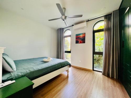 - une chambre avec un lit et un ventilateur de plafond dans l'établissement Villa SB03 Road in Vinhome Ocean Park 1, à Gia Lâm Pho