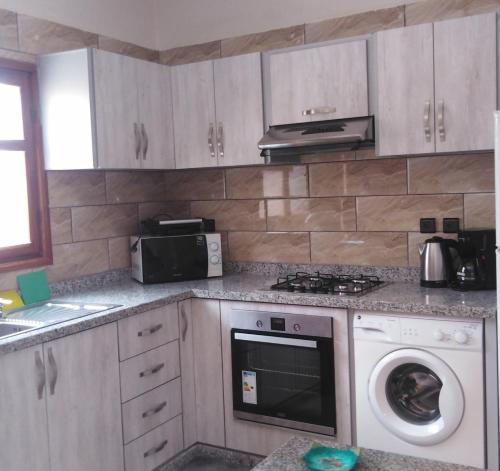 a kitchen with a stove and a washing machine at Mirleft Tayought Guest House in Mirleft
