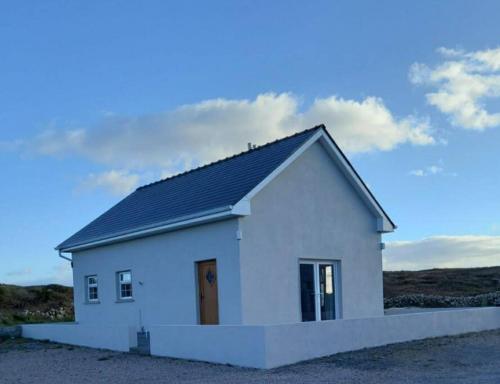 a small white house with a black roof at Radharc an Chuain 2 Bedroom Holiday Home in Galway