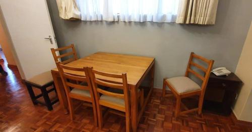 a wooden table with four chairs and a telephone at EMBASSY COURT SERVICED APARTMENTS in Nairobi