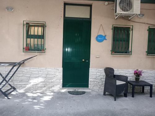 a green door on a building with a table and a chair at Matteo's House Taormina in Taormina