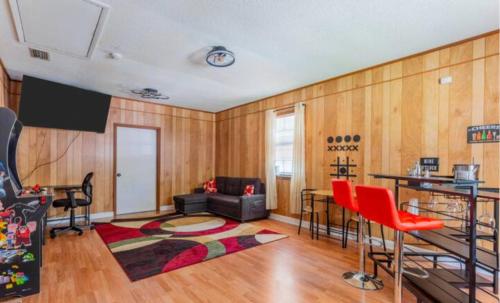 a living room with wooden walls and red chairs at Golden Isles Lrge Home- Huge Pool, Hot Tub, Game Rm in Brunswick