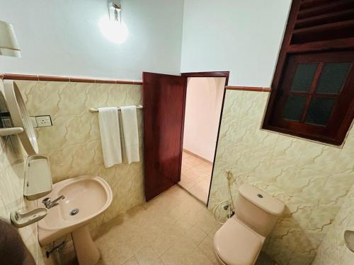 een badkamer met een wastafel, een toilet en een douche bij Funky Hotel in Hikkaduwa