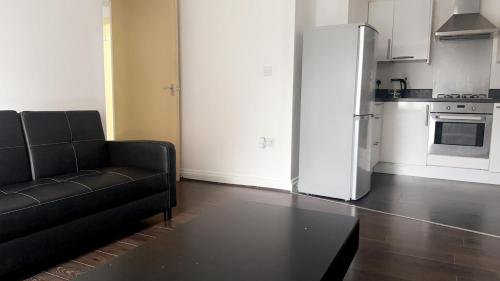 uma sala de estar com um sofá e um frigorífico em 2 bedroom apartment, free parking & WIFI near City Centre em Manchester