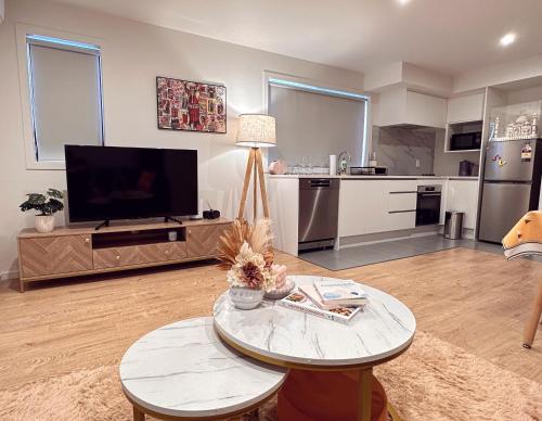 a living room with a table and a tv and a kitchen at Brandnew modern apartment in Auckland