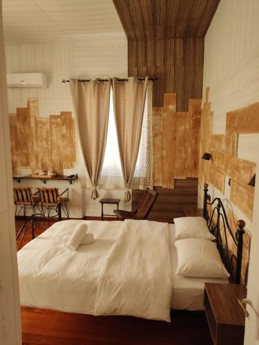 Un dormitorio con una gran cama blanca y una ventana en 1920s Rooms en Kalamata