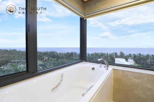 a bath tub in a bathroom with a large window at The South-Sunset in Hengchun South Gate