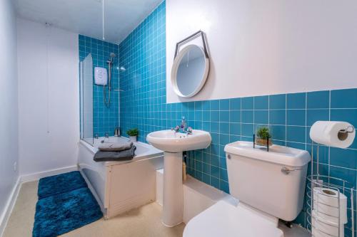 a blue tiled bathroom with a toilet and a sink at PRIMEEE LOCATION - Modern Central Apartment in Bristol