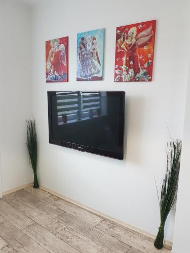a flat screen tv hanging on a wall with pictures at Apartament Angelo in Sosnowiec