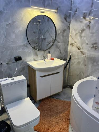 Un baño con lavabo, inodoro y espejo. en Luxury boutique, en Chişinău