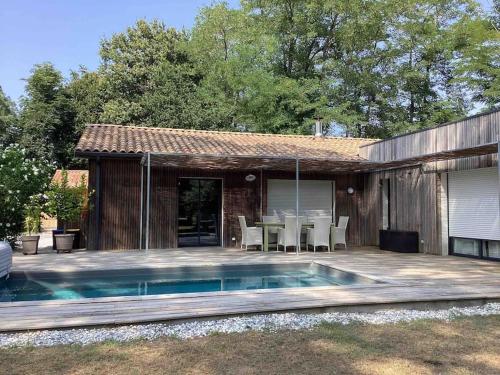 un patio avec une table et une piscine dans l'établissement La Maison Tipasa, à Saint-Julien-en-Born