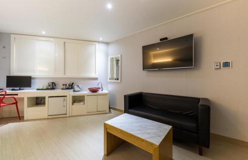 a living room with a black couch and a kitchen at Daesan Hotel in Seosan