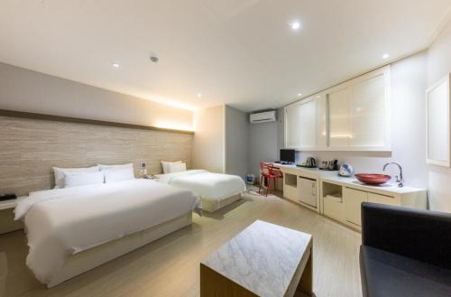 a hotel room with two beds and a kitchen at Daesan Hotel in Seosan