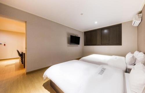 a bedroom with two white beds and a flat screen tv at Daesan Hotel in Seosan
