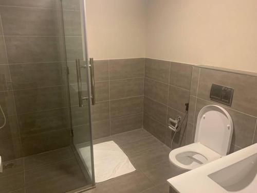 a bathroom with a toilet and a glass shower at Contemporary 2-Bedroom Apartment in Al Qurayyah