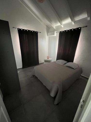 una camera da letto con un letto grande con tende nere di Gîtes Surya a Port-Louis