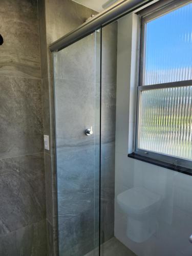 a bathroom with a shower with a toilet and a window at Flat 335 - excelente localizacão, estacionamento in Teresópolis