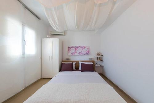 um quarto com uma grande cama branca com almofadas roxas em Uno Apartment 2 em Livadia