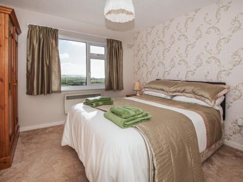 a bedroom with a bed with green towels on it at Island View in Aberdaron