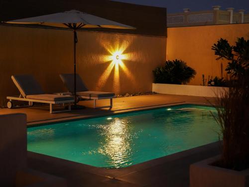 una piscina con sombrilla, mesa y sillas en O2 pool villa en Ras al-Khaimah