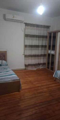 een slaapkamer met een bed en een houten vloer bij سكن طلاب الازاريطة in Alexandrië