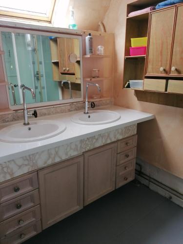 uma casa de banho com 2 lavatórios e um espelho grande em L'Atelier em Lannion
