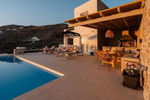 eine Terrasse mit einem Tisch und Stühlen sowie einem Pool in der Unterkunft Pleiades Villas Naxos2 (Hottub) in Agkidia