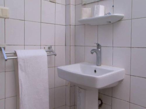 biała łazienka z umywalką i ręcznikiem w obiekcie Centre Ecotouristique de Bagré w mieście Saré