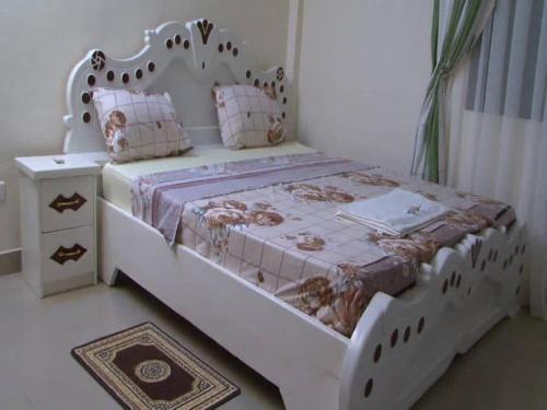 sypialnia z białym łóżkiem z drewnianym zagłówkiem w obiekcie Centre Ecotouristique de Bagré w mieście Saré