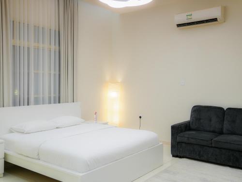 1 dormitorio con 1 cama y 1 silla negra en O2 pool villa, en Ras al Khaimah