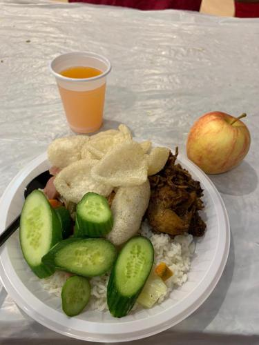 un plato de comida con carne y arroz y una manzana en Permata homestay, en Karawang