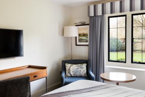 a hotel room with a bed and a chair and a table at voco Oxford Thames by IHG in Oxford