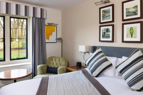 a hotel room with a bed and a chair at voco Oxford Thames by IHG in Oxford