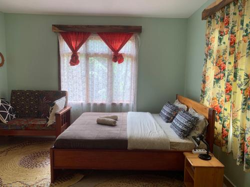 a bedroom with a bed with a window and a chair at David Crater Homestay in Lushoto